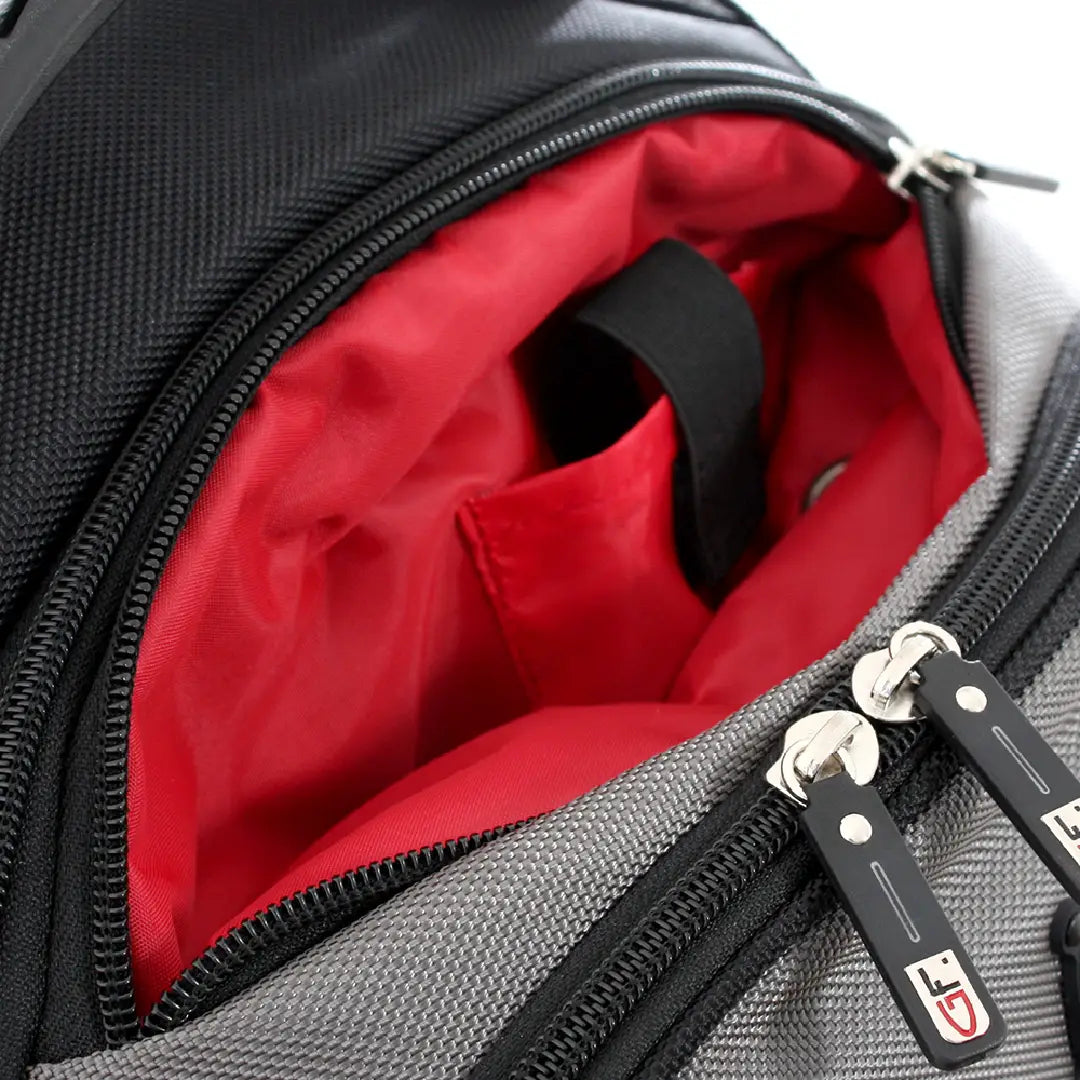 Close-up of an open gray and black backpack showing a bright red interior lining with a black handle and silver zipper pulls.