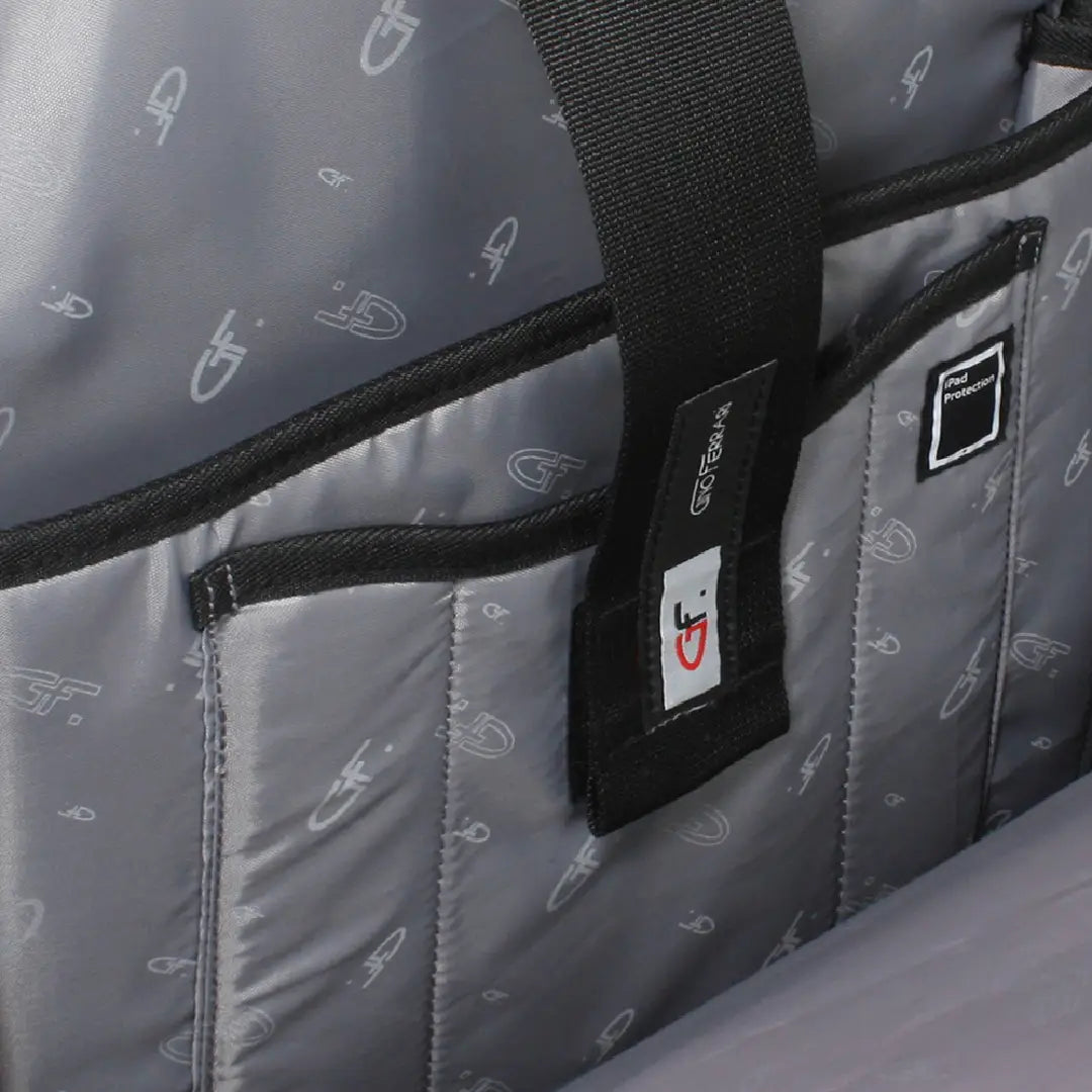 Close-up of a gray quilted bag with a black strap and multiple brand patches, including a square patch and a smaller rectangular patch with a red and black logo.