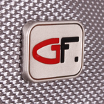Close-up of a metallic badge featuring the stylized letters 'G' and 'F' with a red 'G' and black 'F' on a textured gray background.