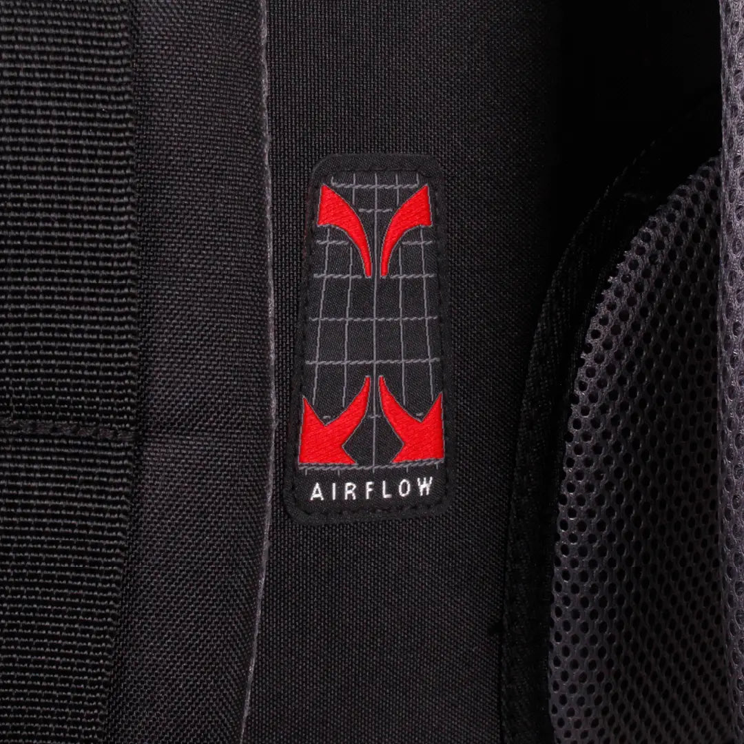 Close-up of a black backpack fabric with a rectangular black patch featuring red abstract wing-like shapes and the word AIRFLOW in white text.