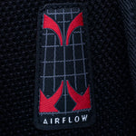 Close-up of a black mesh fabric patch with a red and gray grid design and the word AIRFLOW in white at the bottom.