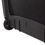 Close-up of the lower corner of a black wheeled suitcase, showing a black fabric side panel, black plastic base trim, and a black caster wheel on a white background.