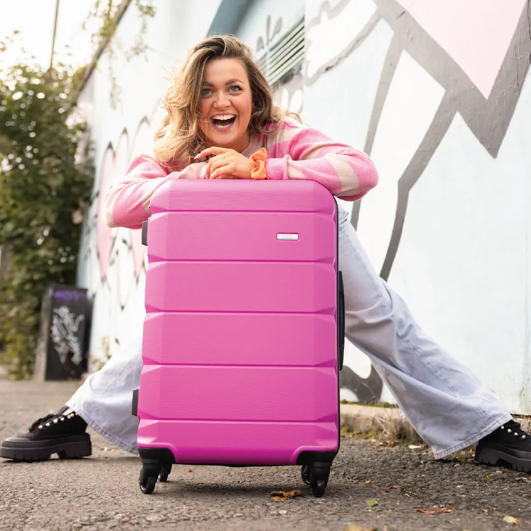 Woman leaning on a pink suitcase outdoors
