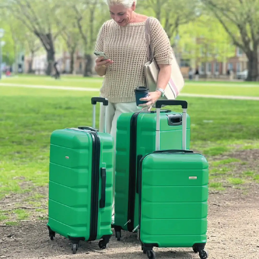 Woman with three green suitcases all different sizes in a park