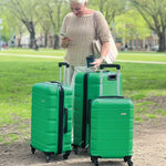 Woman with three green suitcases all different sizes in a park