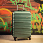 Green suitcase on a wooden floor with a colorful graffiti wall in the background