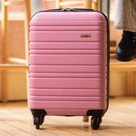 Pink suitcase with a brand logo on a wooden floor