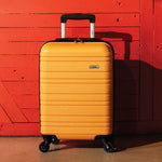 Yellow suitcase with black handle and wheels against a red wooden background