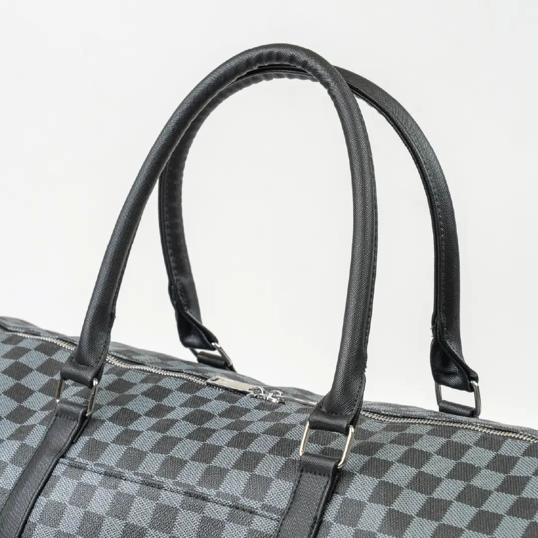 Checkered duffel bag with black handles on a light gray background
