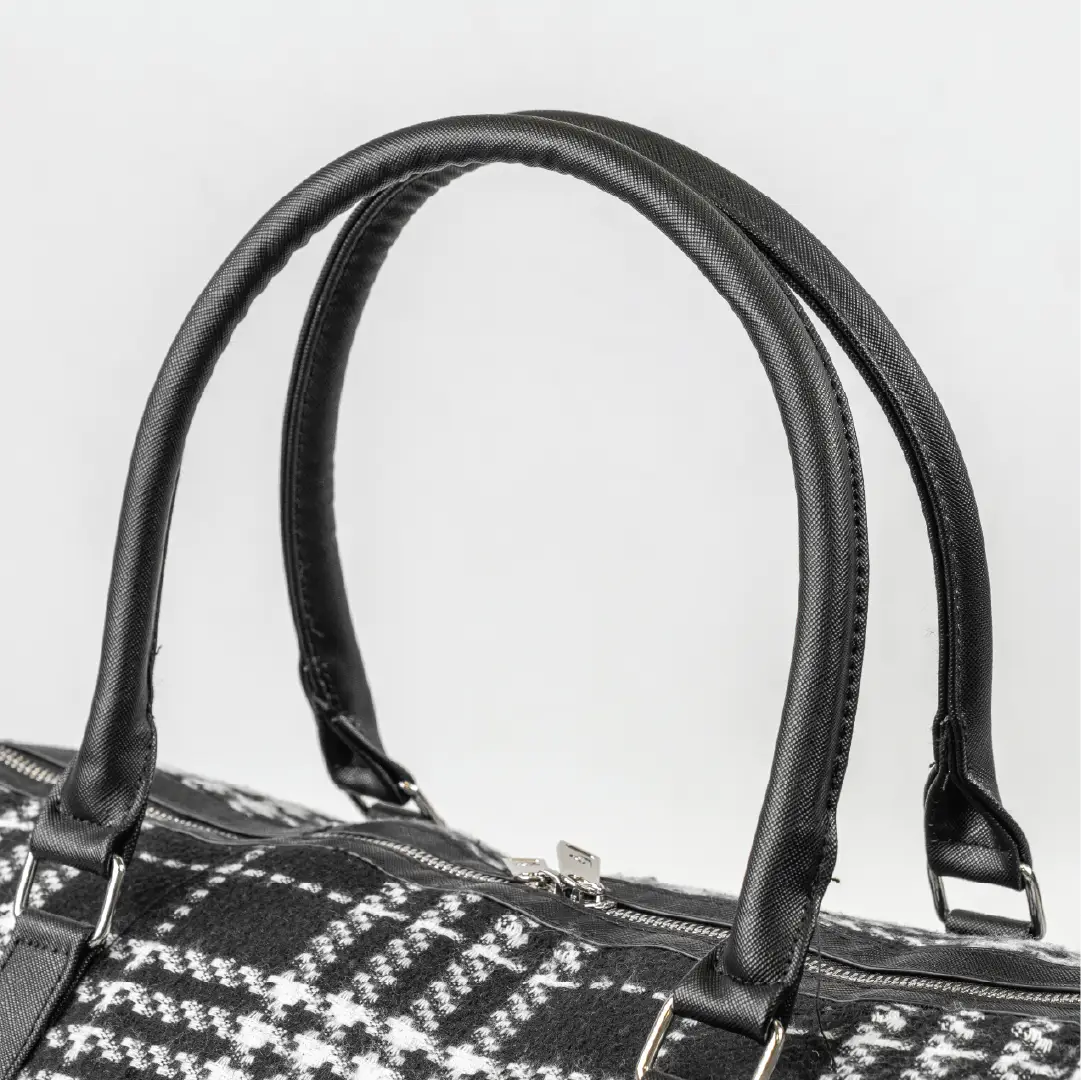 Close-up of a black and white patterned handbag with handles on a light gray background