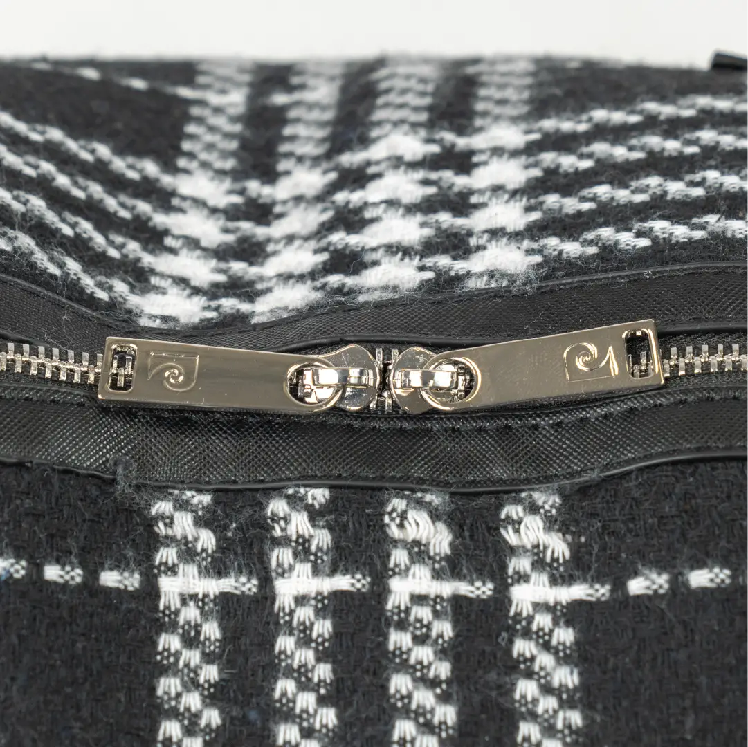 Close-up of a black and white patterned bag with a silver zipper and brand logo.