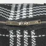 Close-up of a black and white patterned bag with a silver zipper and brand logo.