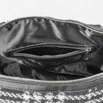 Close-up of a black leather handbag with a zipper, showing the interior.