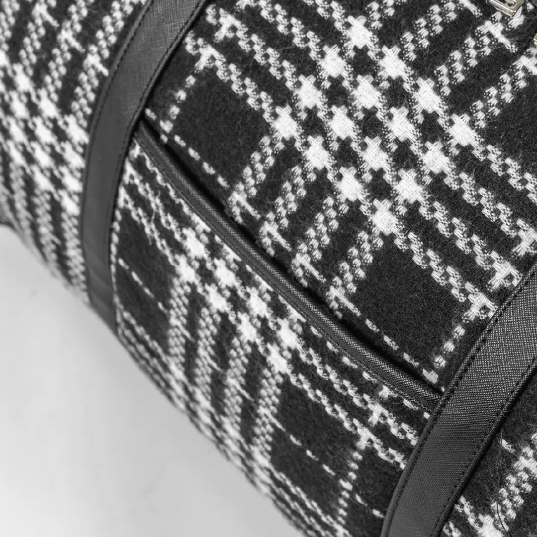 Close-up of a black and white checkered bag with a zipper on a light gray background