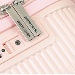 Close-up of a pink suitcase with 'Pierre Cardin' branding on a metallic tag.