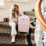 Woman sitting on a staircase with a pink suitcase