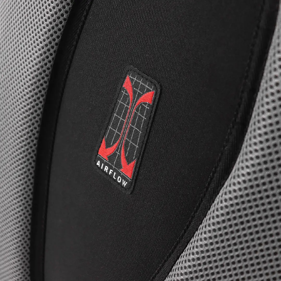 Close-up of a black backpack or bag panel with a visible AIRFLOW logo patch, surrounded by gray mesh fabric.