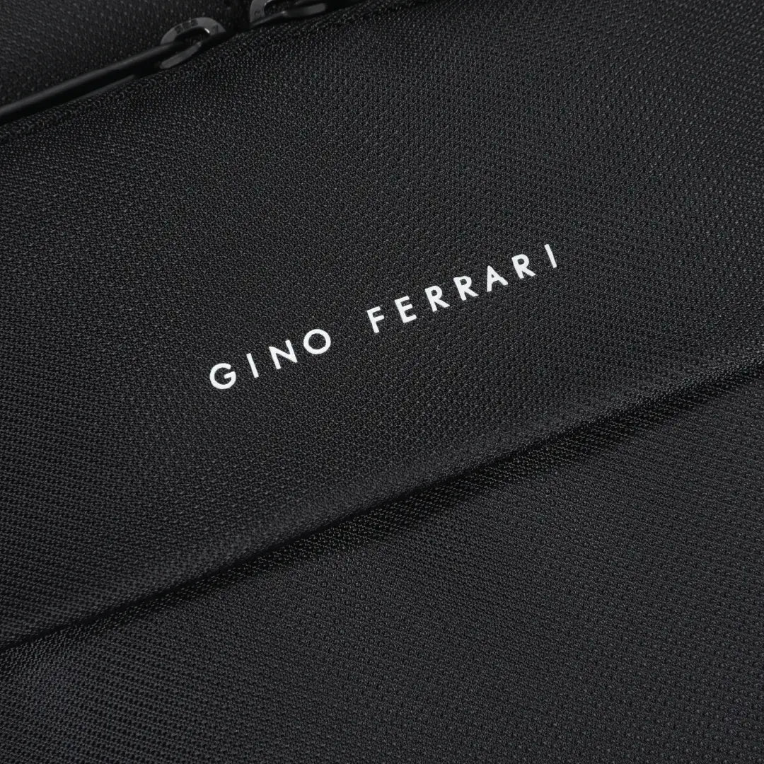 Close-up of a black textured fabric bag with white embroidered text reading 'Gino Ferrari' and a zipper edge at the top.
