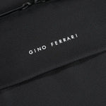 Close-up of a black textured fabric bag with white embroidered text reading 'Gino Ferrari' and a zipper edge at the top.