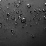 Close-up of a dark textured surface covered with scattered water droplets, showing a waterproof or hydrophobic finish.