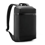 A black minimalist backpack with a top handle and adjustable shoulder straps, shown from an angle on a white background.