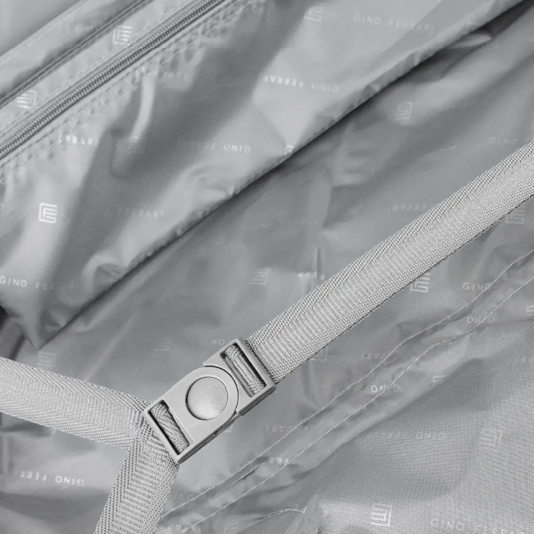 Close-up of a suitcase with a strap and buckle, featuring a brand logo.