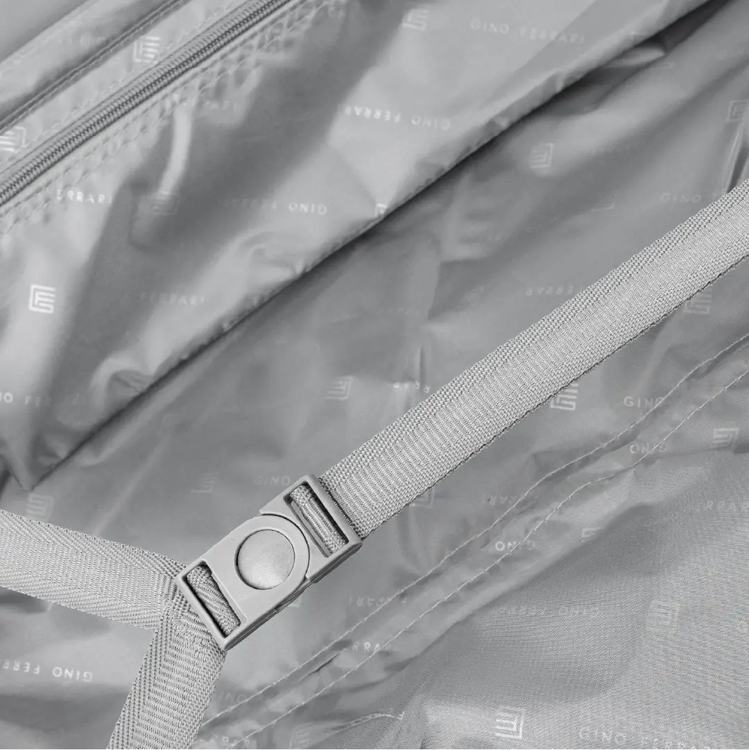 Close-up of a the inside of a suitcase with a strap and buckle, featuring the brand.