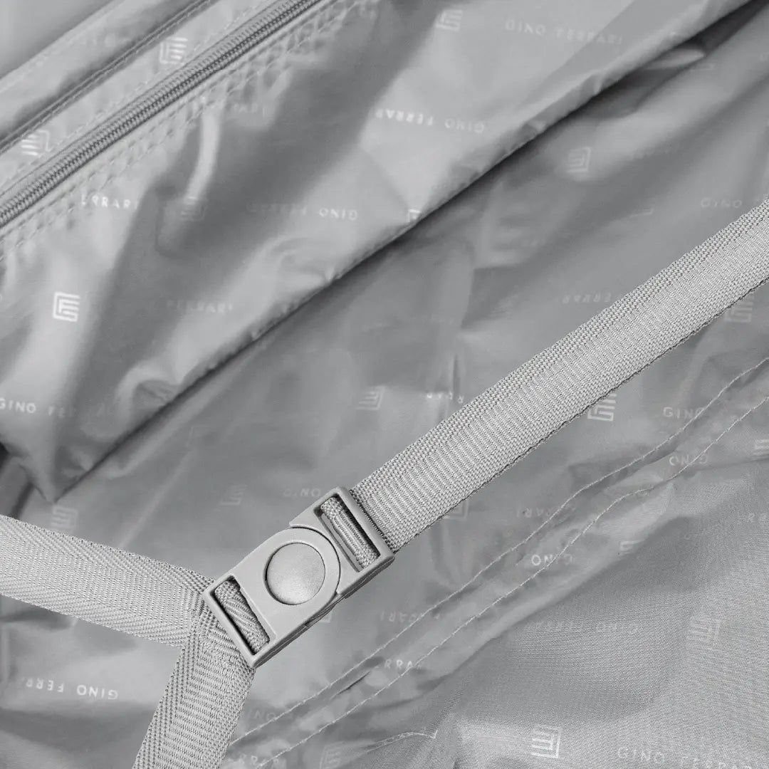 Close-up of a gray bag with a strap and buckle, featuring the brand.