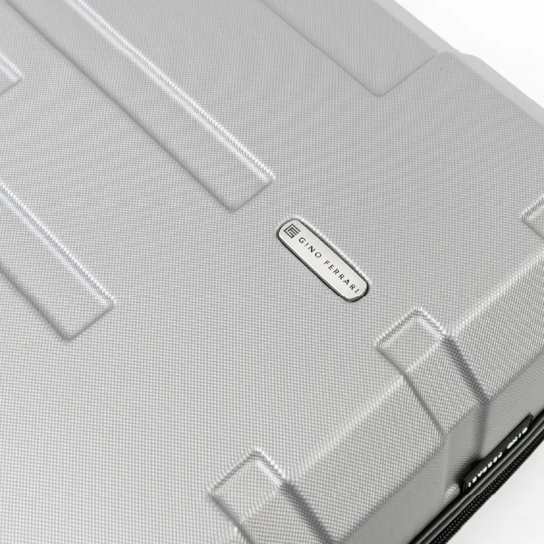 Close-up of a silver suitcase with a brand logo.