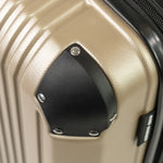 Close-up of a gold hard-shell suitcase with black accents.