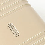 Close-up of a gold hard-shell suitcase with a visible brand logo 'Gino Ferrari'.