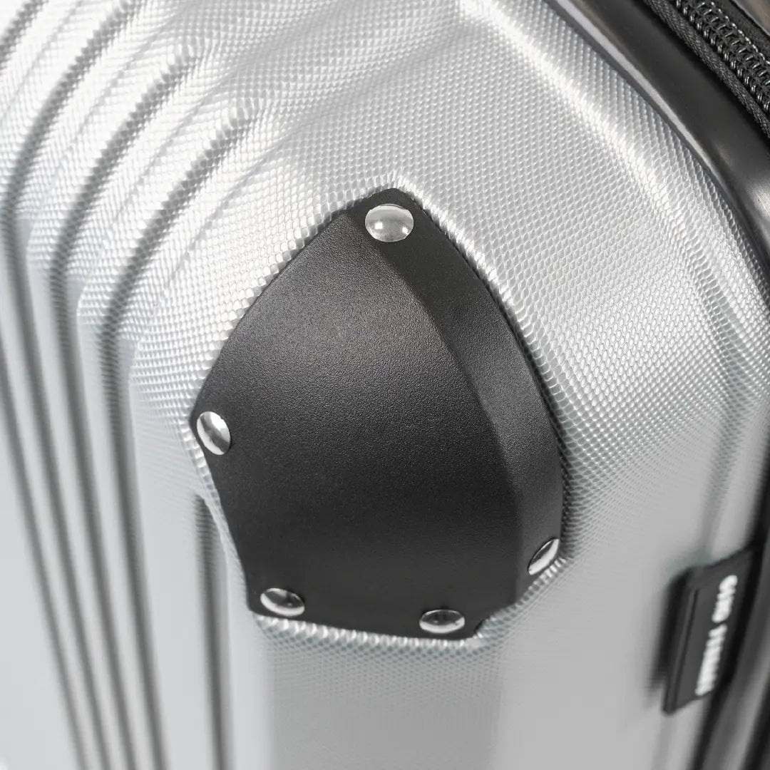 Close-up of a silver hard-shell suitcase with black corner.