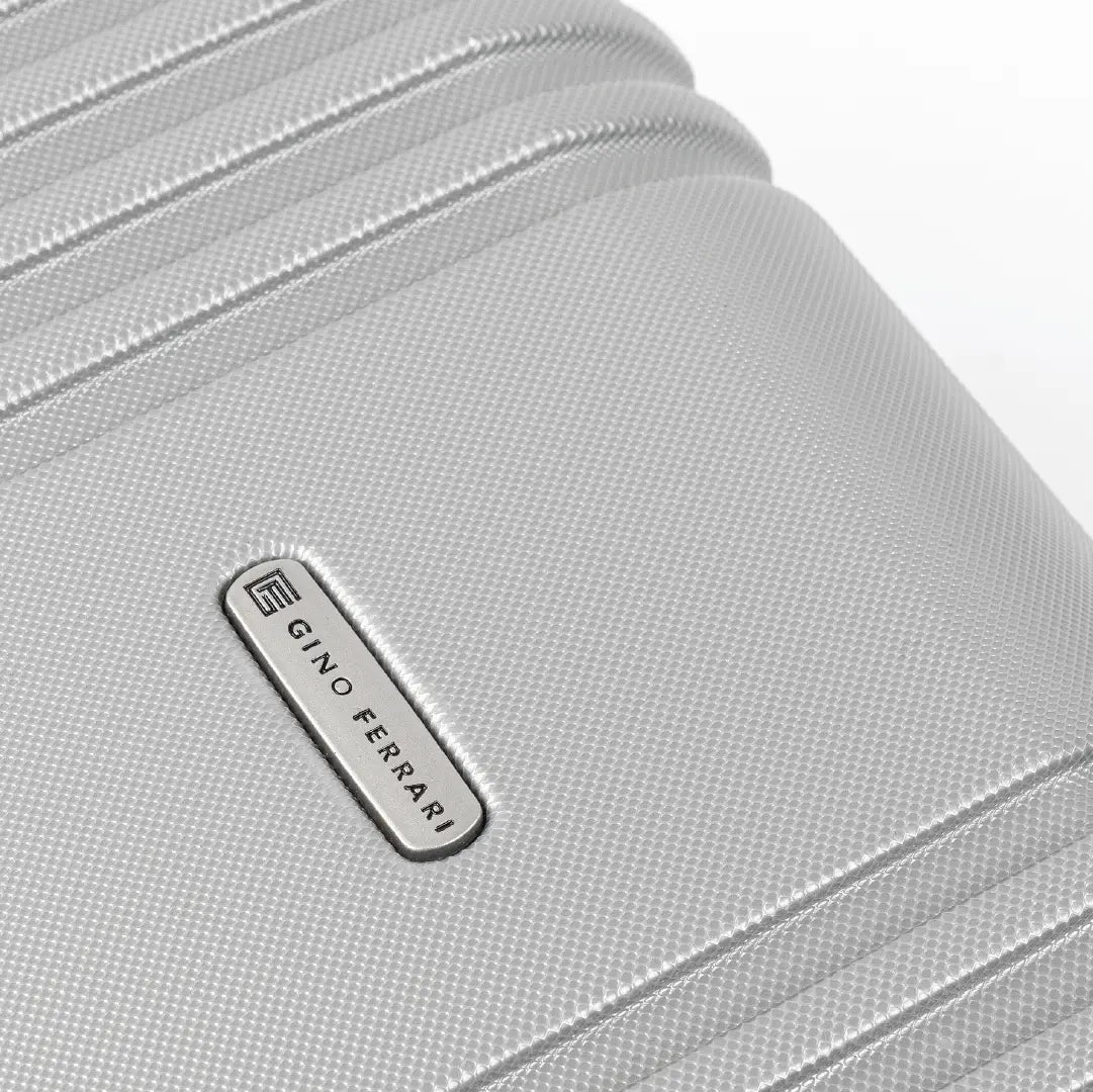 Close-up of a silver hard-shell suitcase with the brand logo 'Gino Ferrari' visible.