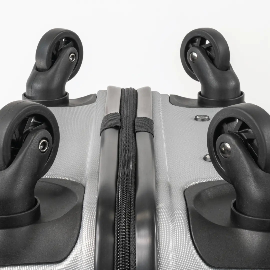 Close-up of the bottom of a silver suitcase showcasing the wheels and zip.