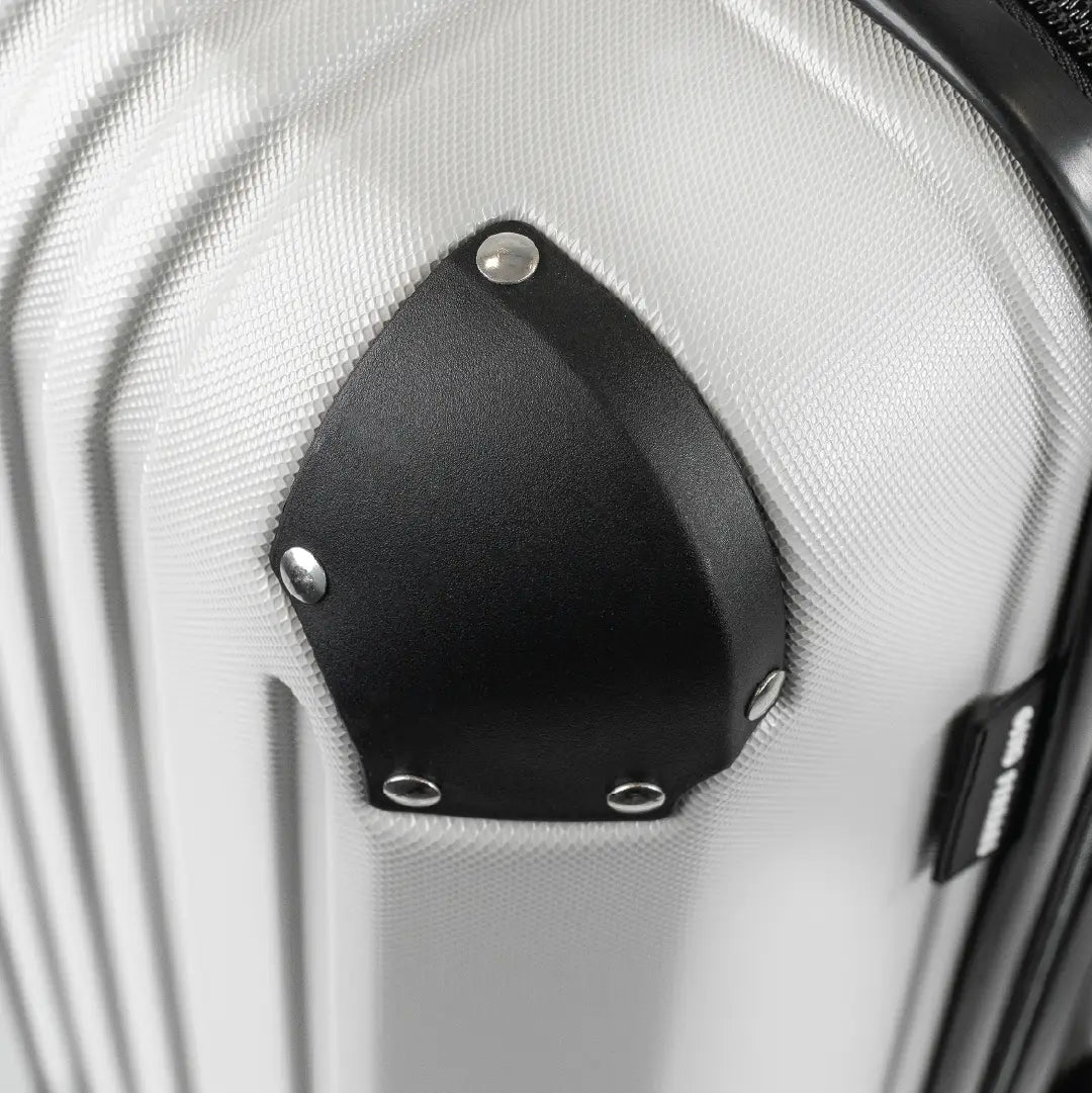Close-up of a silver hard-shell suitcase with a visible brand logo and black accents.