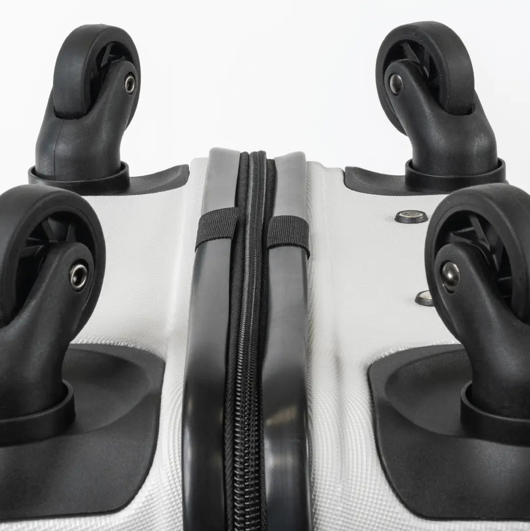 Close-up of the bottom of a silver suitcase showcasing the wheels and zip.