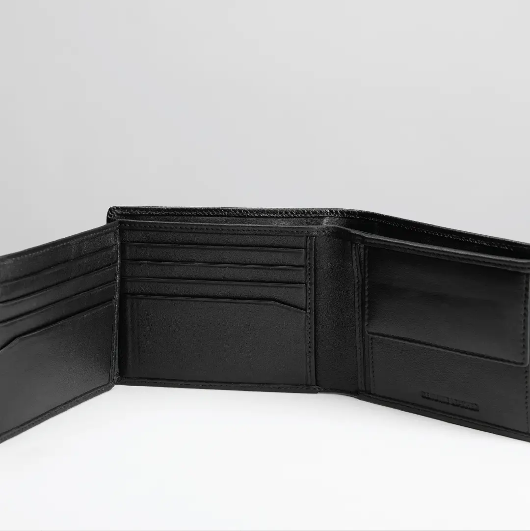 An open black leather bifold wallet displayed against a light gray background, showing its interior card slots and pockets.