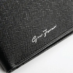 Close-up of a black textured leather clutch or wallet with a white script logo reading 'Gino Ferrari' on a white background.