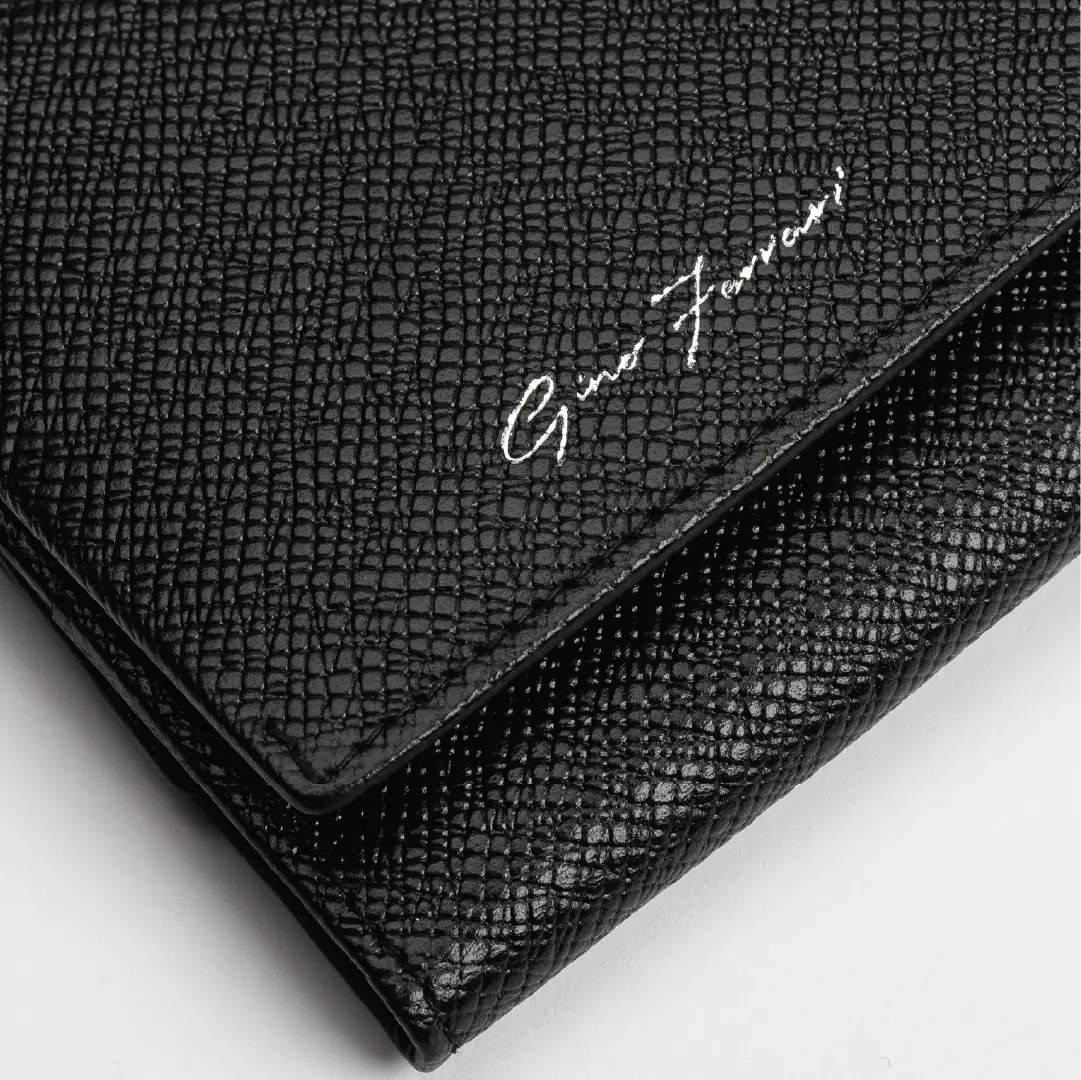 A close-up of a black textured leather clutch or wallet with a silver-tone script logo reading 'Gino Ferrani' on a white background.