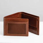 A brown leather bi-fold wallet shown open, displaying its interior card slots and a front ID window with a textured insert, set against a clean light gray background.