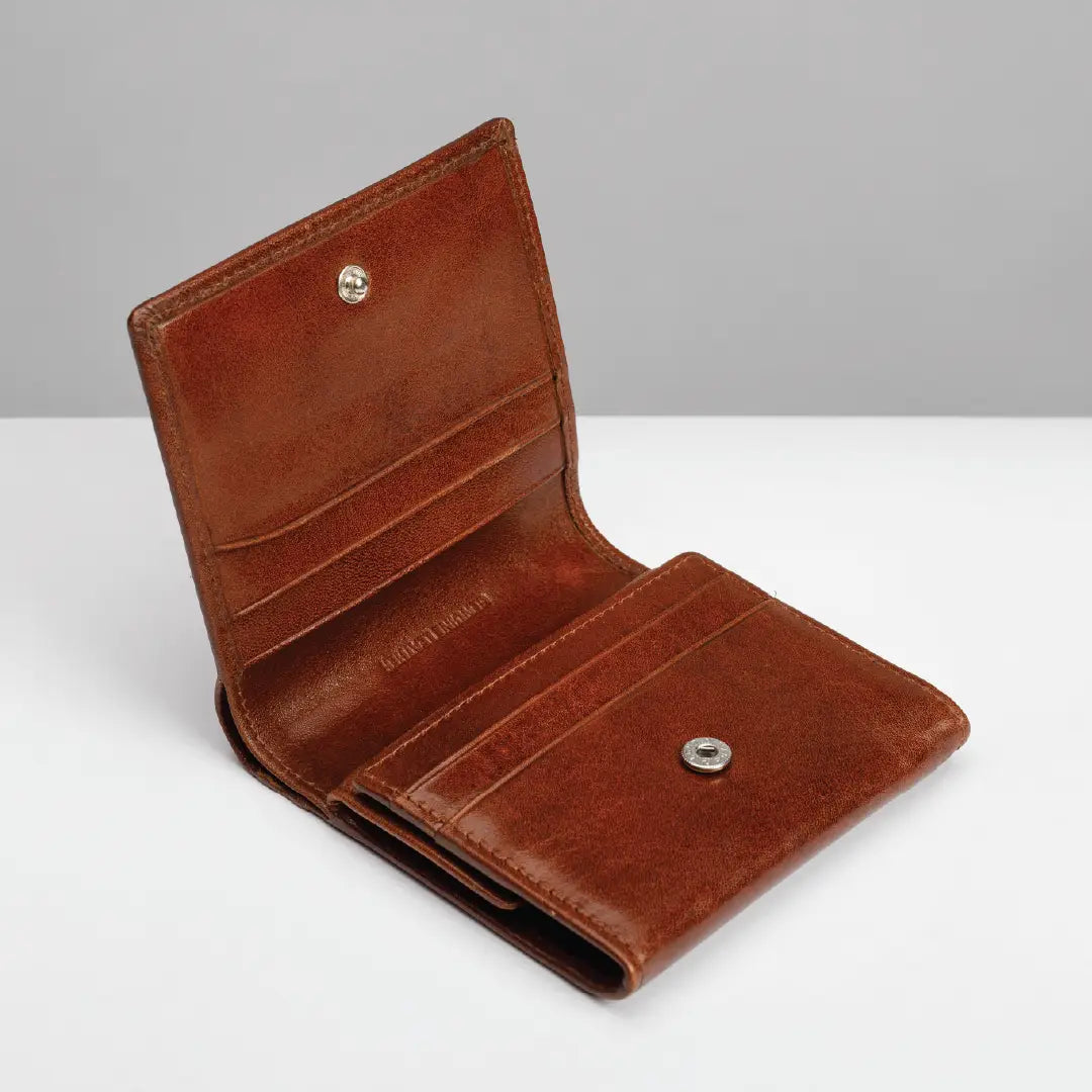 A brown leather bi-fold wallet shown open, displaying its interior card slots, a snap-button closure, and a debossed brand name on the inside.