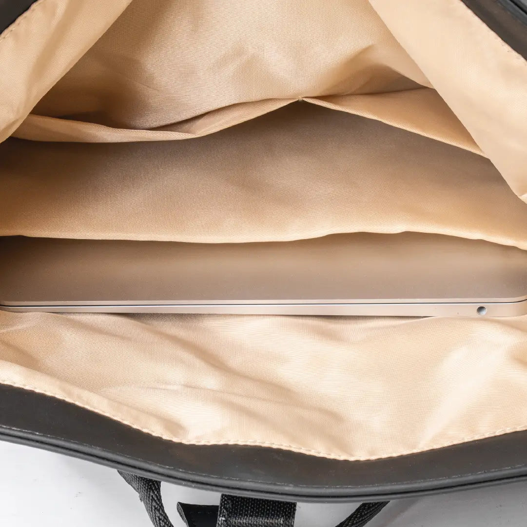 Close-up of a laptop inside a bag with beige interior.