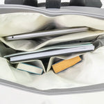 Open bag with compartments holding a tablet, books, and a wooden item.