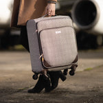 Person holding a textured suitcase with an airplane in the background