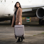 Woman holding a suitcase on an airport tarmac with an airplane in the background