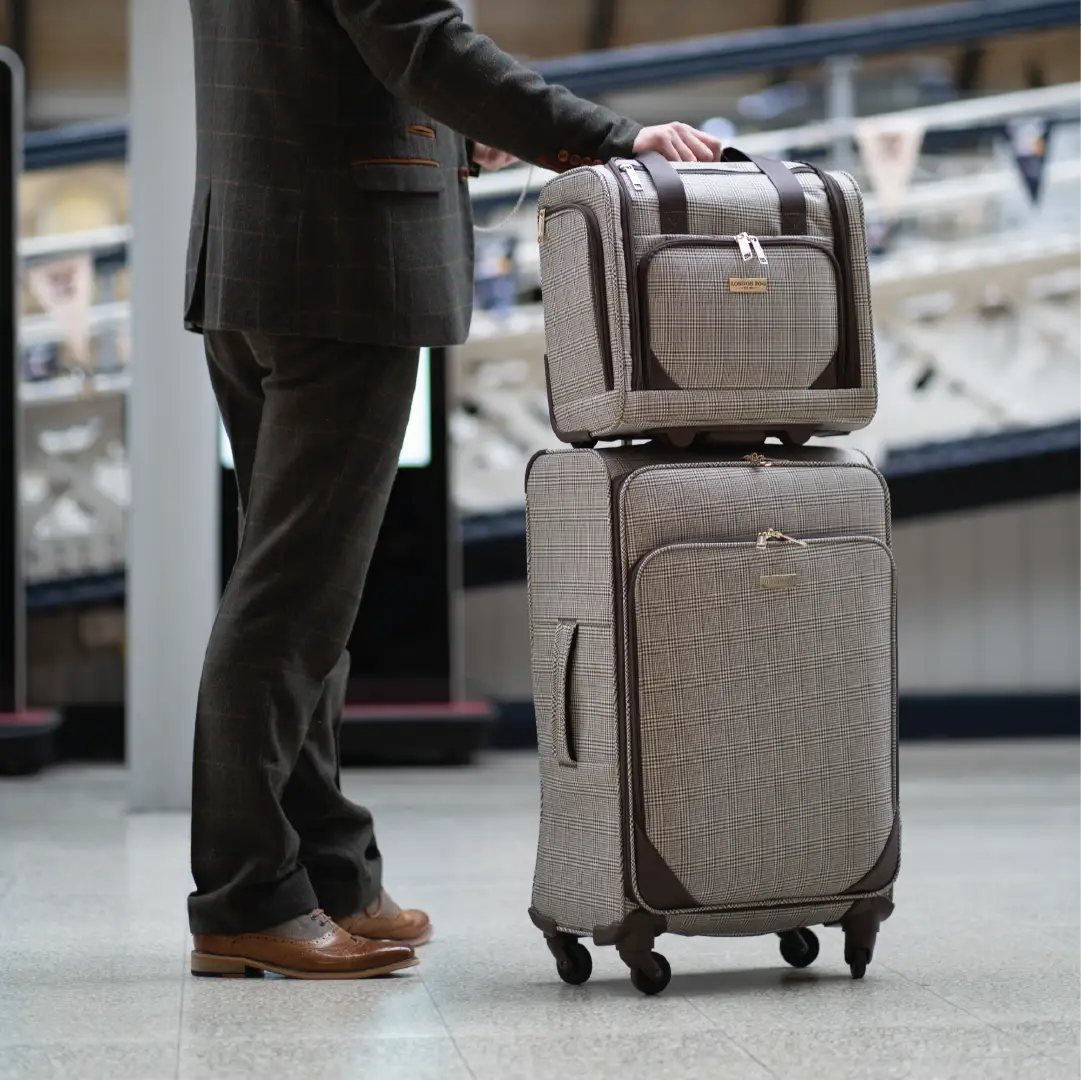 Person in a suit with two stacked suitcases in an airport setting