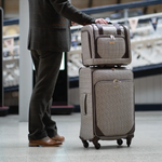 Person in a suit with two stacked suitcases in an airport setting