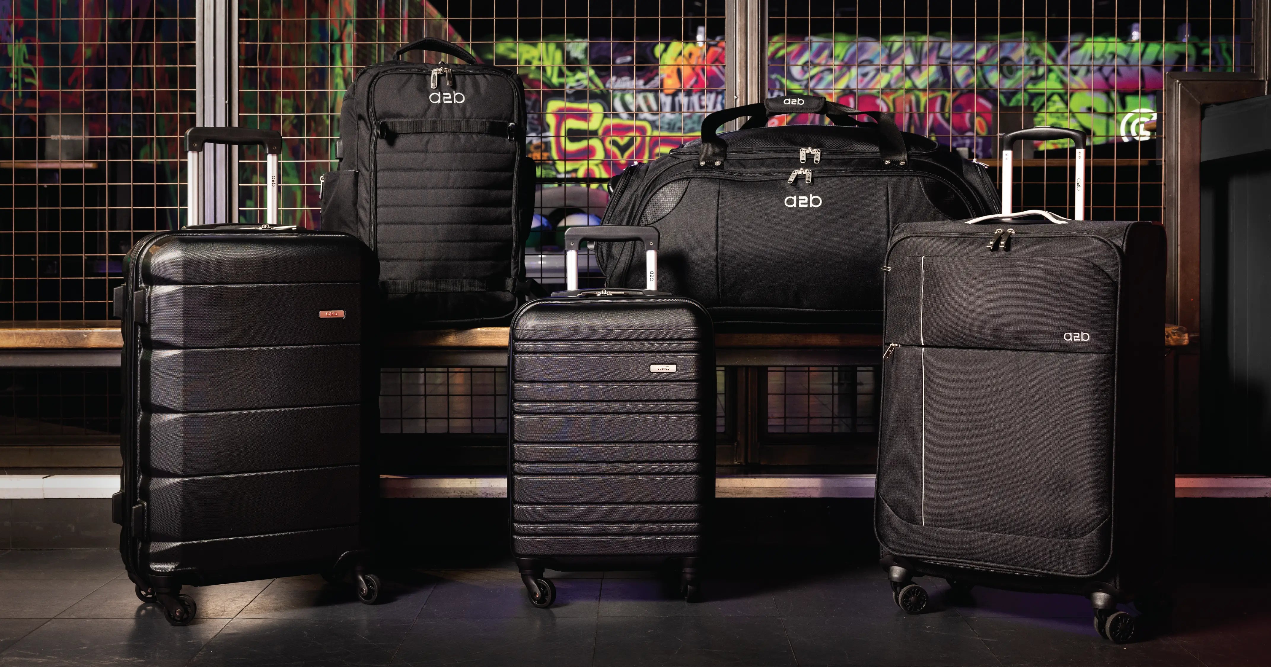 Collection of black suitcases and backpacks on a dark background with colorful graffiti.