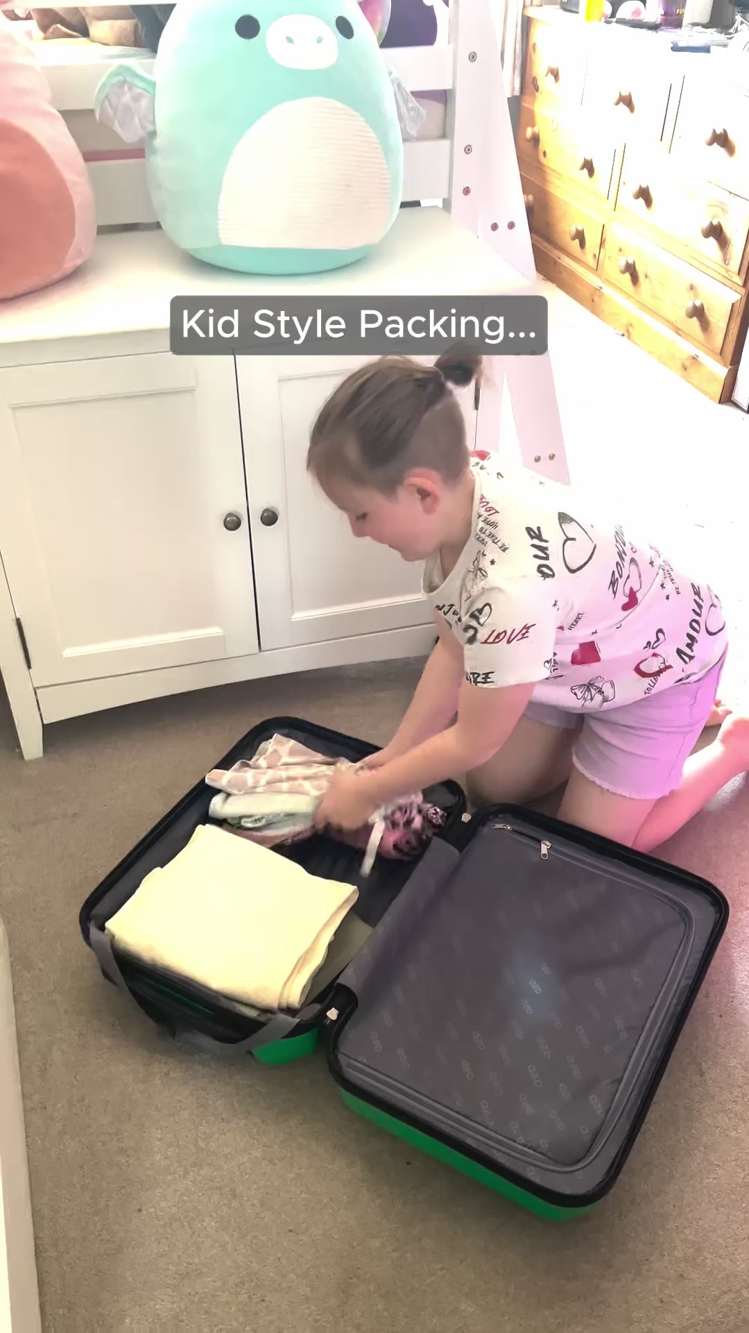 Child packing a small green suitcase to go on holiday with all of their essentials.